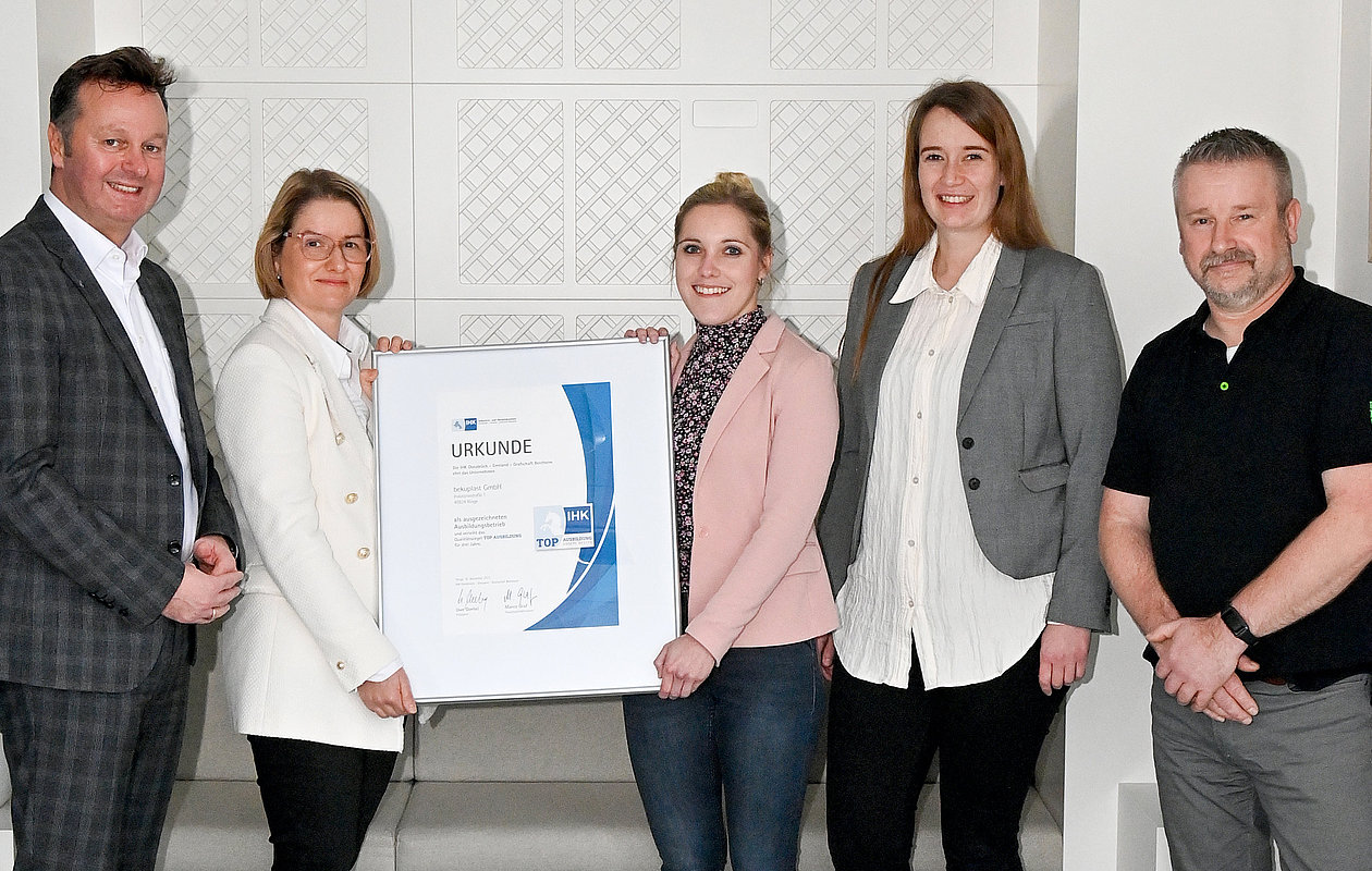 Team von bekuplast mit einer Auszeichnung der IHK für hervorragende Ausbildungsqualität, stehend im Büro, als Anerkennung für das Engagement in der Ausbildung junger Menschen in verschiedenen Berufsfeldern und Beitrag zur regionalen Fachkräftesicherung.